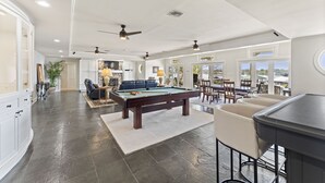 A spacious living area with a pool table, seating, and a view of the outdoors. - Beautiful False River Home on water w/ Dock (New Roads)