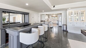 A modern kitchen with a bar area, white cabinetry, and a large mirror. - Beautiful False River Home on water w/ Dock (New Roads)