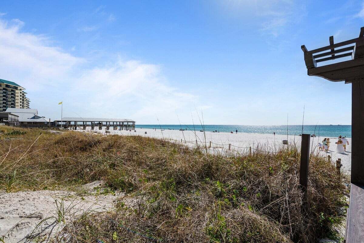 A beach with a wooden structure, a pier, and buildings in the background.