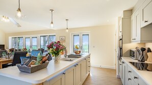 A modern kitchen with a large island, built-in appliances, and large windows.