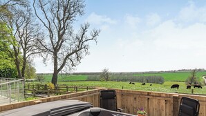A hot tub with a view of a green field and cows.