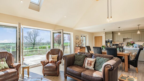 A spacious living area with a leather sofa, a glass coffee table, and a dining table.
