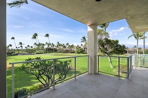 A balcony with a view of a golf course and palm trees.