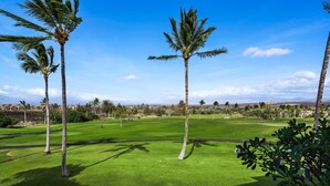 Een golfbaan met palmbomen en een heldere lucht.