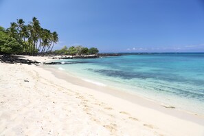 A beach with clear turquoise water, white sand, and palm trees. - Vista Waikoloa G204 (Waikoloa)