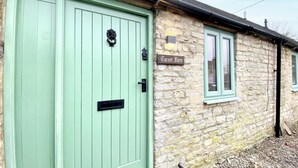 A stone building with a green door and a sign reading "Carner Barn". - 2 bedroom accommodation in Cirencester (Cirencester)