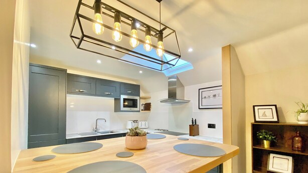 A modern kitchen with a central island, a microwave, and a built-in oven. - 2 bedroom accommodation in Cirencester (Cirencester)