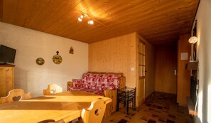 Un intérieur en bois comprenant une table à manger, des chaises, un canapé et un téléviseur.