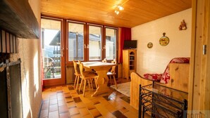 A wooden interior with a dining table and chairs, a sofa, and a television. - Small apartment on the ski slopes (Gryon)