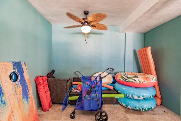 A room with a ceiling fan, a wall-mounted TV, and a bed with pillows and a blanket.