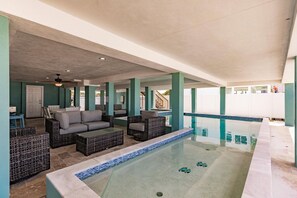 An indoor swimming pool area with lounge seating and a view of the outside.
