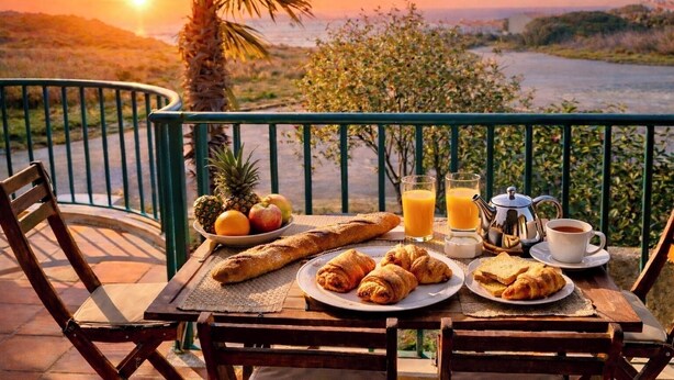 A table set with croissants, fruit, juice, and coffee on a balcony overlooking a scenic view. - Casa Da luz 5, ocean view, pool & beach 200 meters away  (Praia da Luz)