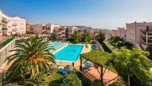 A resort with a central swimming pool surrounded by lounge chairs and palm trees. - Casa Da luz 5, ocean view, pool & beach 200 meters away  (Praia da Luz)