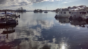 A marina with boats docked, calm water, and a clear sky.