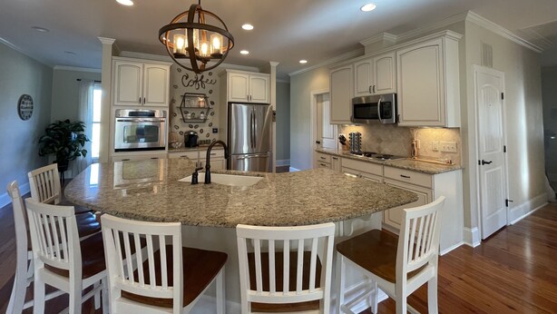 A modern kitchen with white cabinetry, a granite island, and a chandelier. - Modern farm Home Close to Jordan lake and Downtown apex (Apex)