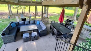 A covered patio with a sectional sofa, a dining table, and a grill. - Modern farm Home Close to Jordan lake and Downtown apex (Apex)