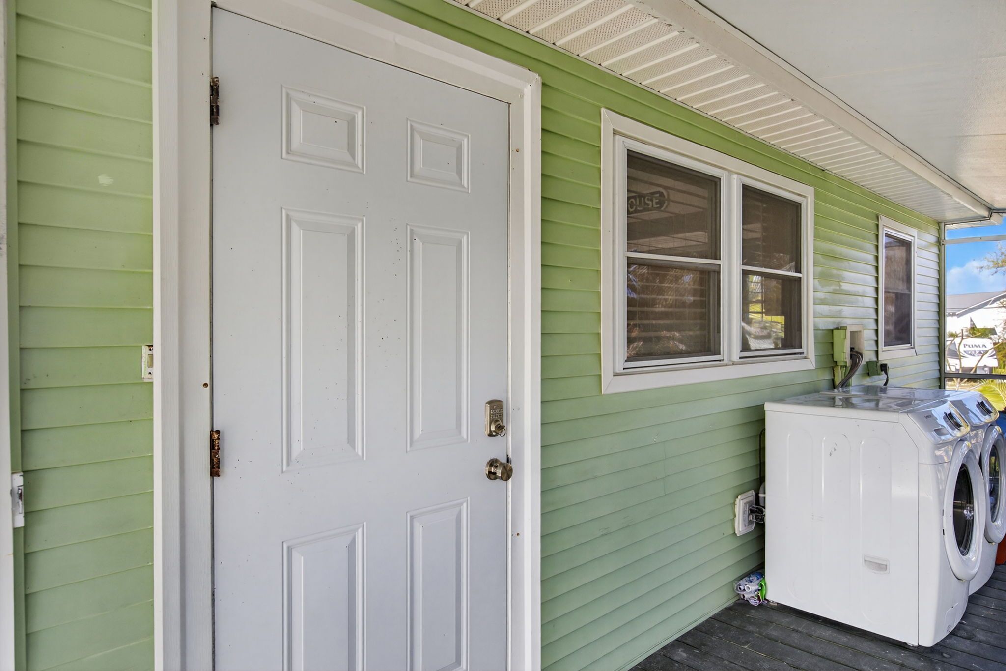 A green house with a white door and a window with a 'HOUSE' sign.