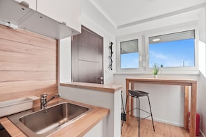 A modern kitchen with a stainless steel sink, wooden countertop, and a window with a view of the sky. - Prime View Apartment Zagreb (Zagreb)