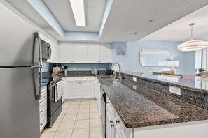 Een moderne keuken met granieten aanrecht, roestvrijstalen apparatuur en een dakraam.