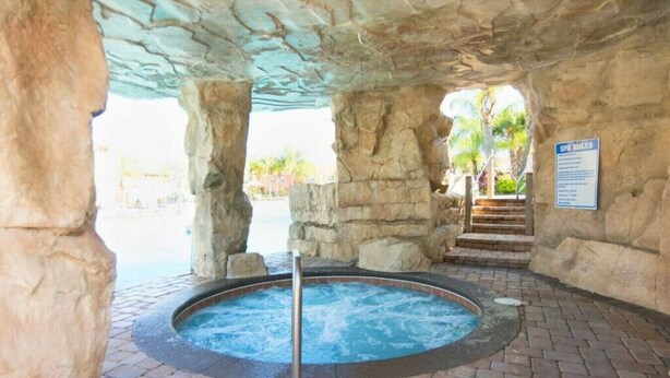 A spa area with a hot tub, stone walls, and a sign detailing spa rules. - Resort acess walking distance - Private pool (Kissimmee)