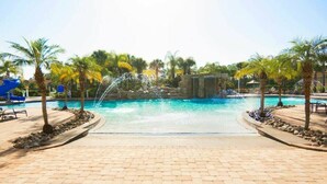A pool area with a clear view of the water, surrounded by palm trees and a paved walkway. - Resort acess walking distance - Private pool (Kissimmee)
