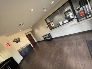 Un vestíbul ampli amb terra de fusta, una taula de recepció, una decoració amb forma de corona a la paret i una porta que dona a una zona de cuina.