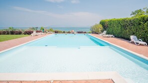 A rectangular swimming pool with a clear view of the ocean in the background. - Vista Lago Apartment (Sirmione)