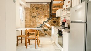 Una cocina compacta con pared de piedra, escalera de madera y electrodomésticos modernos.