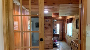 Ein Korridor mit Holzausbau, der zu einem Raum mit Fenster und dem Schild ‚STEP DOWN‘ führt.