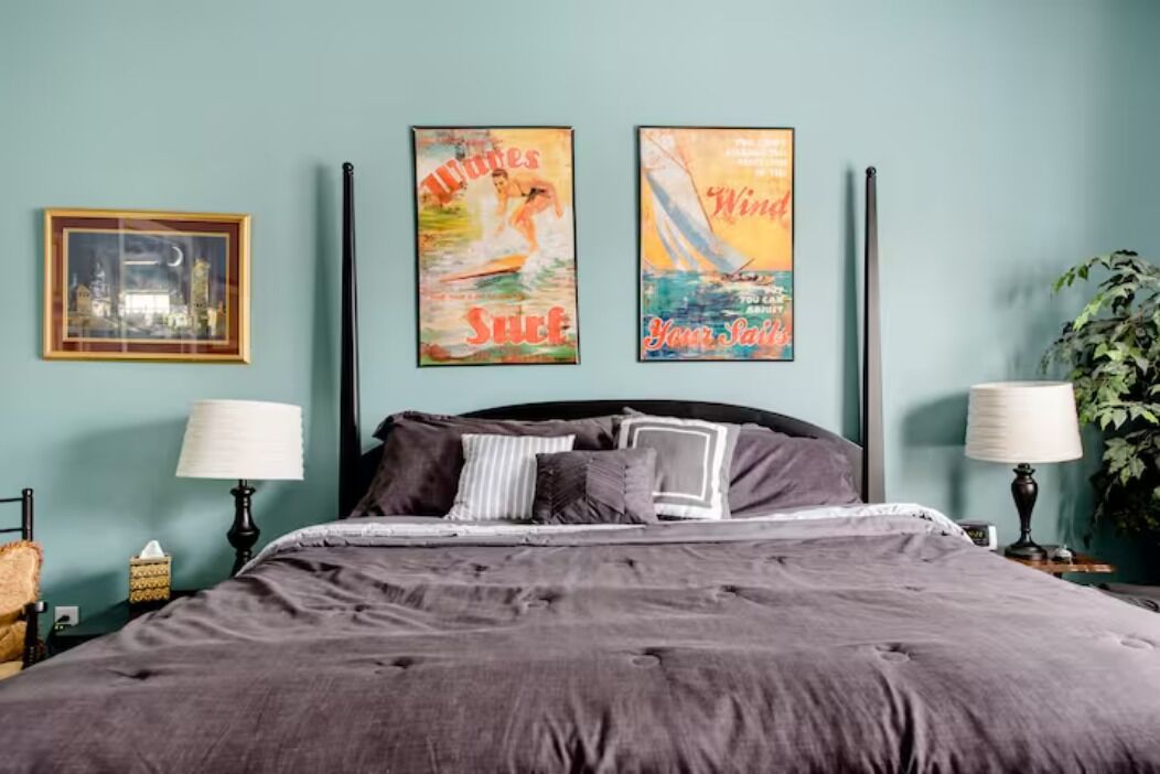 A bedroom with a large bed, two wall-mounted lamps, and two posters on the wall.