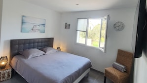 Un dormitorio con una cama, una silla, un reloj de pared y una ventana.
