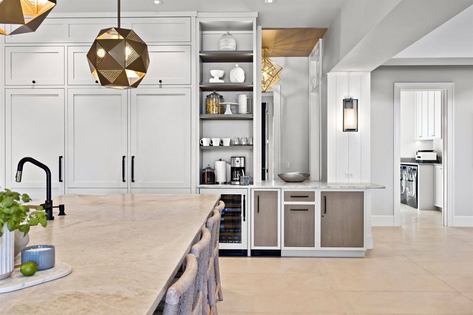 A modern kitchen with white cabinetry, a marble countertop, and a central island.