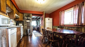 A kitchen with wooden cabinets, a dining table with chairs, and a refrigerator.
