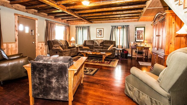 A cozy living room with wooden beams, leather sofas, and a wooden coffee table.