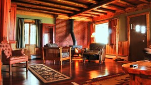 A cozy living room with a fireplace, leather chairs, a sofa, and a wooden coffee table.