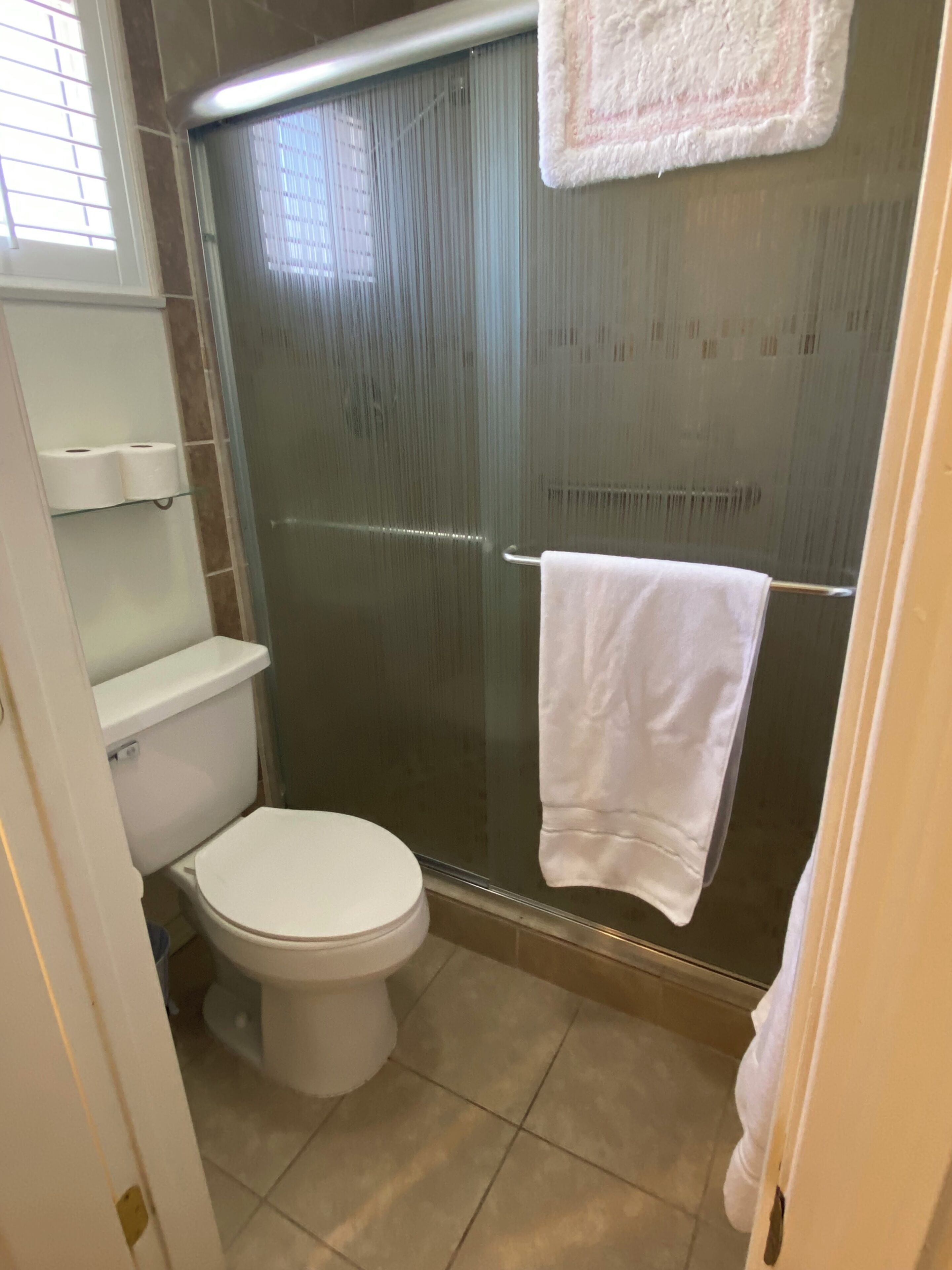 Ein Badezimmer mit Toilette, einer Duschkabine aus Glas und einem Handtuch an der Wand.