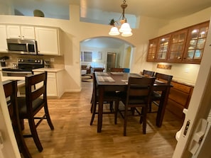 Una cocina con armarios de madera, una mesa de comedor con sillas y un microondas.