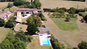 Ett flygbildsfoto av en bostadsfastighet med en swimmingpool, flera byggnader och omgivande grönska.
