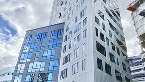En modern skyskrapa med en blandning av glas- och betongfasader, flera våningar och en markant hörnkonstruktion.