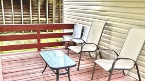 Una terraza de madera con una mesa y cuatro sillas.