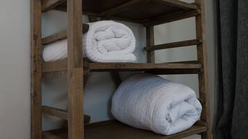 A wooden shelf with three rolled white towels.