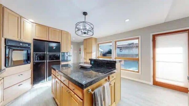 A spacious kitchen with wooden cabinets, a black countertop, and a central island. - Spacious 6BR Home with Hot Tub, Hammocks and Firepit (Denver)
