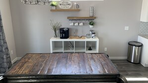 A modern kitchen with a wooden dining table, white cabinetry, and a coffee station. - Brand new, 3 bedroom piece of  paradise! (Grand Junction)
