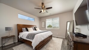 A bedroom with a bed, a ceiling fan, a TV, a dresser, and a window with blinds. - Brand new, 3 bedroom piece of  paradise! (Grand Junction)