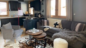 Ein modernes Wohnzimmer mit einem grauen Sofa, einem runden Holztisch und einem Teppich aus Rindsleder.