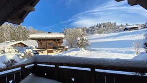 Eine Holzhütte mit schneebedecktem Dach, eingebettet in eine verschneite Landschaft und Bäume.