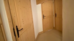 Ein schmaler Korridor mit Holztüren und einer geneigten Decke.