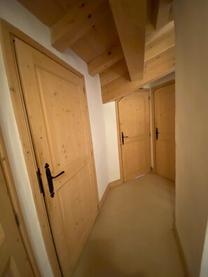 Un couloir étroit avec des portes en bois et un plafond en pente.