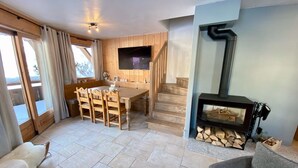 Ein gemütliches Wohnzimmer mit Kamin, ein Essbereich mit Holzmöbeln und eine Treppe, die in ein Obergeschoss führt.