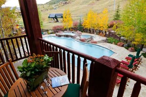 Relax by the serene pool surrounded by a natural rock design and a wooden deck with a table and chairs.